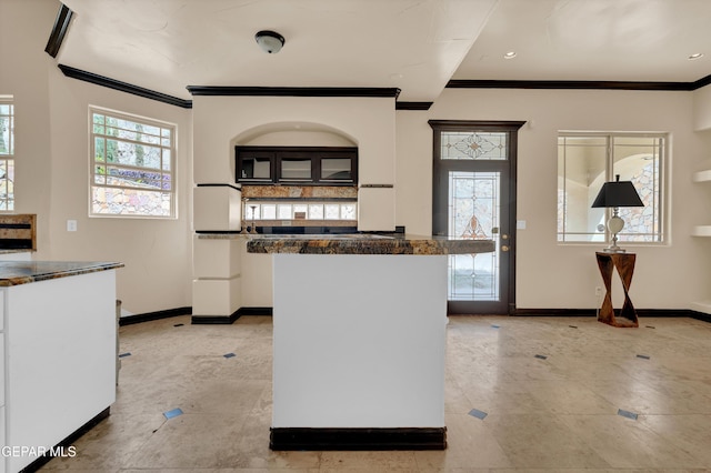 4540 N Stanton St, El Paso, TX 79902 - kitchen with ornamental molding, light tile patterned flooring, white cabinetry, dark countertops, and a kitchen island