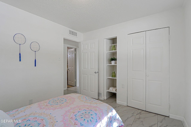 10304 Thor St, El Paso, TX 79924 - bedroom featuring a closet, light marble finish floors, and a textured ceiling