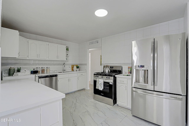 10304 Thor St, El Paso, TX 79924 - kitchen featuring stainless steel appliances, light marble finish flooring, washer / clothes dryer, light countertops, and white cabinets