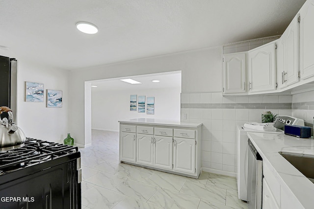 10304 Thor St, El Paso, TX 79924 - kitchen with washer and dryer, gas range, light marble finish flooring, white cabinetry, and tile walls