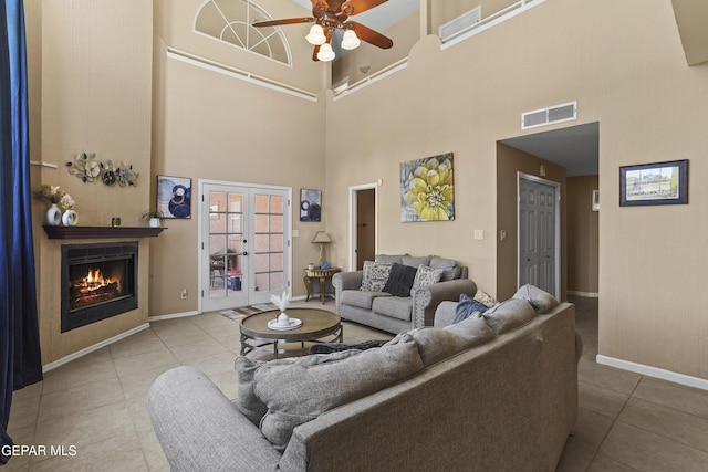 2072 Pueblo Nuevo Cir, El Paso, TX 79936 - tiled living area featuring a high ceiling, a ceiling fan, a lit fireplace, and french doors