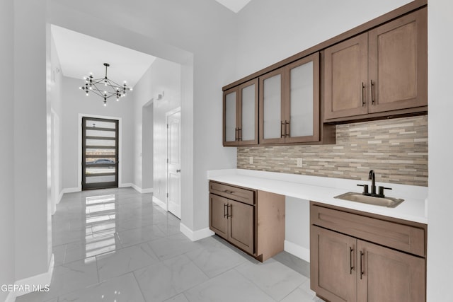 7549 Enchanted Park Dr 706849, El Paso, TX 79911 - kitchen featuring light marble finish flooring, a chandelier, backsplash, glass insert cabinets, and light countertops