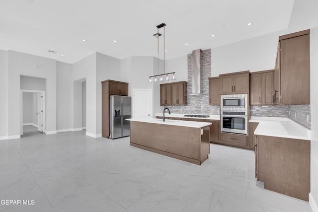 7549 Enchanted Park Dr 706849, El Paso, TX 79911 - kitchen with stainless steel appliances, wall chimney range hood, light marble finish flooring, an island with sink, and tasteful backsplash