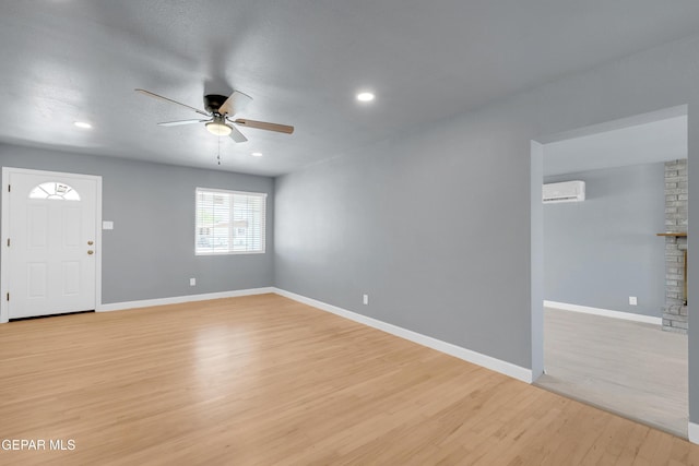 224 Ben Swain Dr, El Paso, TX 79915 - unfurnished living room with a wall unit AC, ceiling fan, light wood-style floors, a fireplace, and recessed lighting