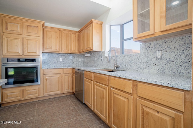 448 Ghost Flower St, Horizon City, TX 79928 - kitchen with appliances with stainless steel finishes, light stone counters, light brown cabinets, decorative backsplash, and glass insert cabinets
