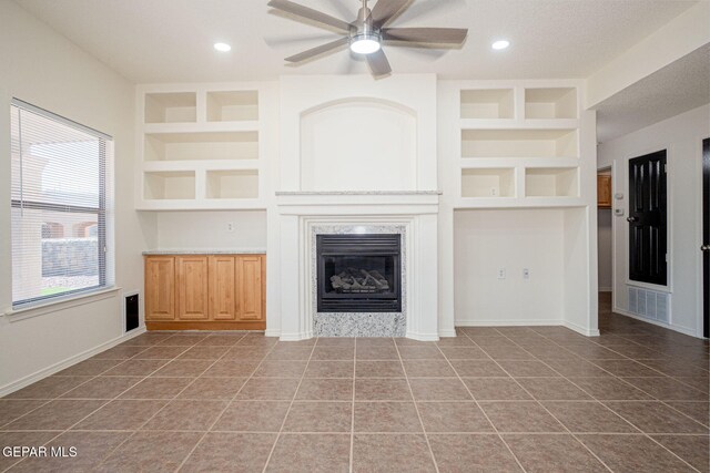 448 Ghost Flower St, Horizon City, TX 79928 - unfurnished living room with a premium fireplace, built in features, a ceiling fan, tile patterned floors, and recessed lighting