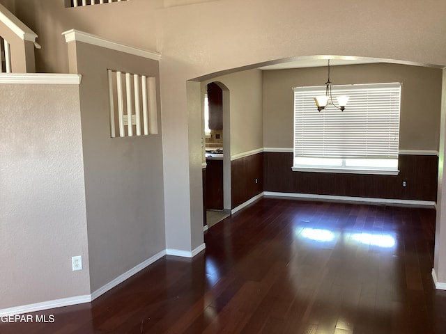 683 Juan Munoz Ct, El Paso, TX 79932 - empty room featuring arched walkways, wood-type flooring, a chandelier, a wainscoted wall, and wood walls