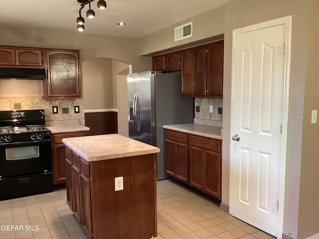 683 Juan Munoz Ct, El Paso, TX 79932 - kitchen with black range with gas cooktop, ventilation hood, arched walkways, light countertops, and tasteful backsplash