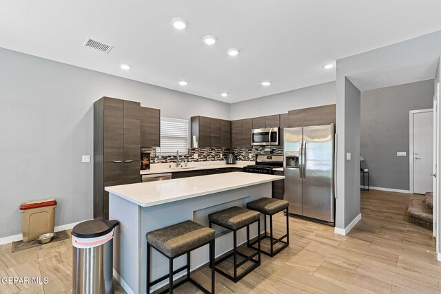 13594 Gatton St, El Paso, TX 79928 - kitchen featuring stainless steel appliances, a kitchen bar, light countertops, dark brown cabinetry, and tasteful backsplash