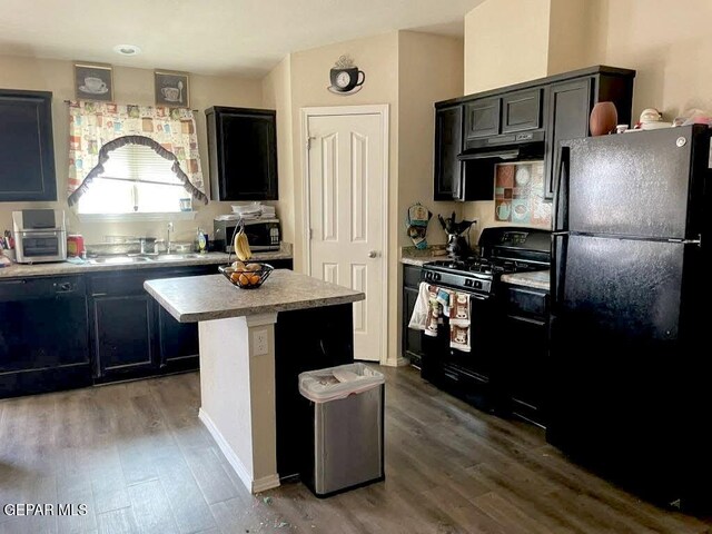 813 Nuevo Desierto Dr, Horizon City, TX 79928 - kitchen featuring black appliances, wood finished floors, under cabinet range hood, a kitchen island, and light countertops