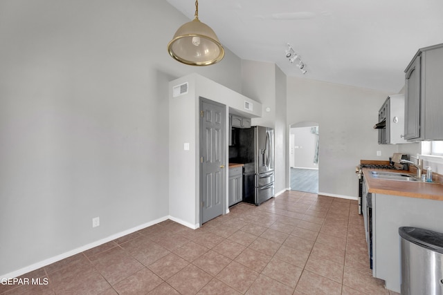 11905 Jim Webb Dr, El Paso, TX 79934 - kitchen featuring arched walkways, stainless steel appliances, light tile patterned floors, gray cabinetry, and rail lighting