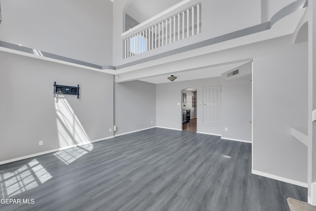 11905 Jim Webb Dr, El Paso, TX 79934 - unfurnished living room with arched walkways, a high ceiling, and dark wood-style flooring