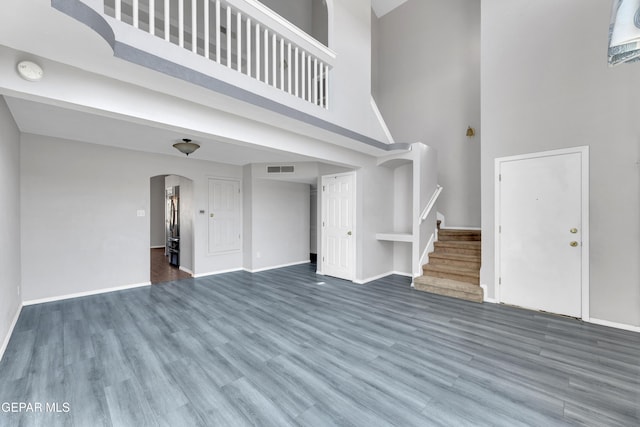 11905 Jim Webb Dr, El Paso, TX 79934 - unfurnished living room with a towering ceiling, arched walkways, wood finished floors, and stairway