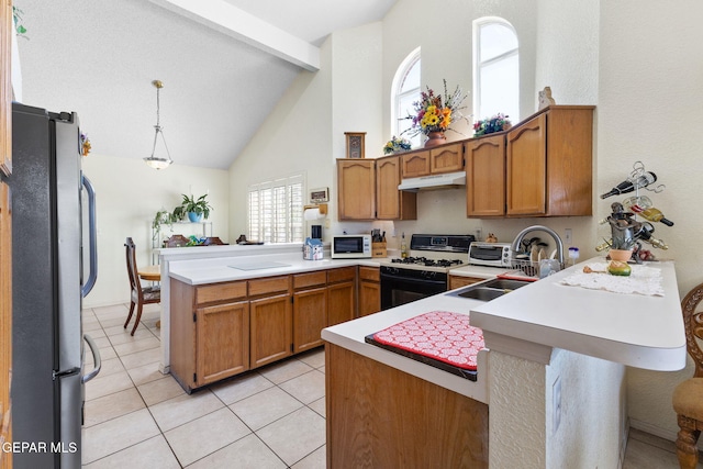 12090 Sterling Mary Way, El Paso, TX 79936 - kitchen featuring freestanding refrigerator, a peninsula, range with gas stovetop, under cabinet range hood, and high vaulted ceiling