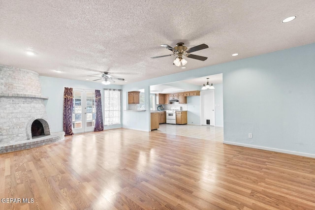 4821 Round Rock Dr, El Paso, TX 79924 - unfurnished living room with a textured ceiling, a ceiling fan, light wood-style floors, a brick fireplace, and recessed lighting