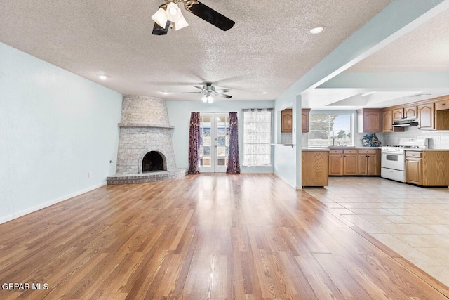 4821 Round Rock Dr, El Paso, TX 79924 - unfurnished living room featuring a ceiling fan, a textured ceiling, light wood finished floors, and a fireplace