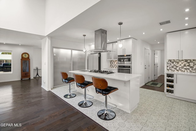 10121 Monaco Dr, El Paso, TX 79925 - kitchen featuring stainless steel double oven, island range hood, a breakfast bar, gas stovetop, and tasteful backsplash