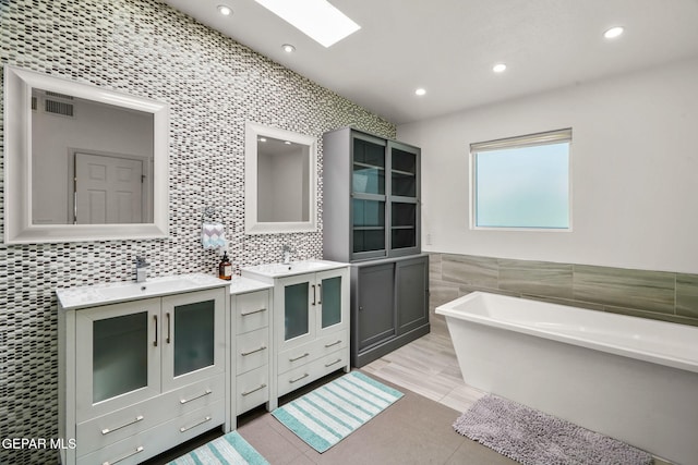 10121 Monaco Dr, El Paso, TX 79925 - bathroom with a soaking tub, tile walls, two vanities, tile patterned flooring, and recessed lighting