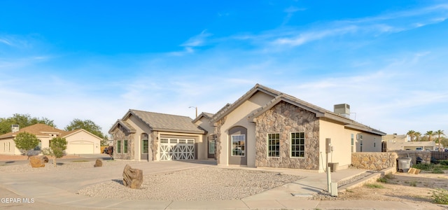 1042 Castillo Ct, El Paso, TX 79932 - back of house featuring stone siding, a garage, stucco siding, and driveway