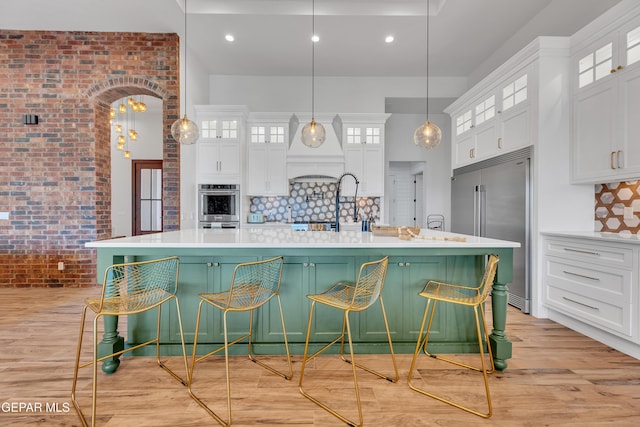1042 Castillo Ct, El Paso, TX 79932 - kitchen featuring stainless steel appliances, white cabinetry, light countertops, brick wall, and a high ceiling