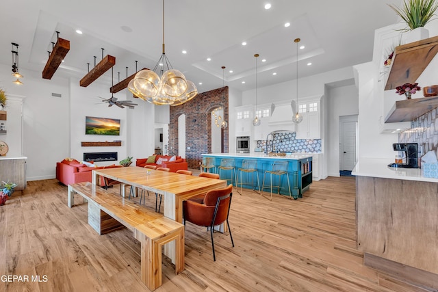 1042 Castillo Ct, El Paso, TX 79932 - dining room with a towering ceiling, a fireplace, recessed lighting, light wood finished floors, and a chandelier