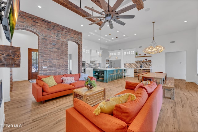 1042 Castillo Ct, El Paso, TX 79932 - living area with a high ceiling, arched walkways, a ceiling fan, light wood-style flooring, and a fireplace