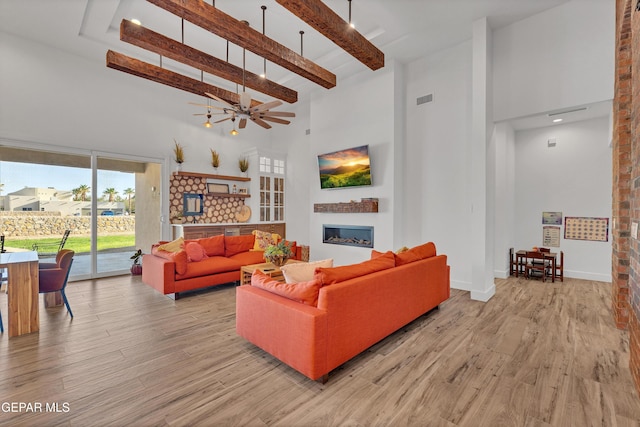 1042 Castillo Ct, El Paso, TX 79932 - living area with a towering ceiling, a glass covered fireplace, light wood-style flooring, and beam ceiling