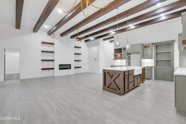 837 Paseo Serra Ct, El Paso, TX 79928 - kitchen with light countertops, open shelves, beam ceiling, a center island with sink, and light wood finished floors
