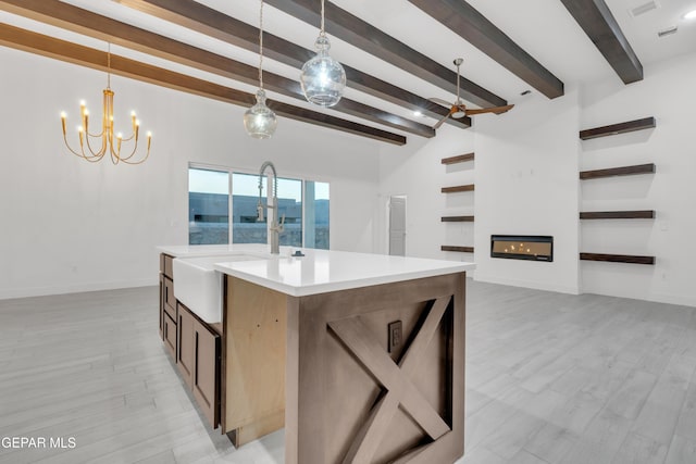 837 Paseo Serra Ct, El Paso, TX 79928 - kitchen featuring light countertops, light wood-style flooring, a glass covered fireplace, hanging light fixtures, and beam ceiling