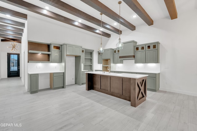 837 Paseo Serra Ct, El Paso, TX 79928 - kitchen featuring beam ceiling, light wood-style floors, a center island with sink, decorative light fixtures, and glass insert cabinets