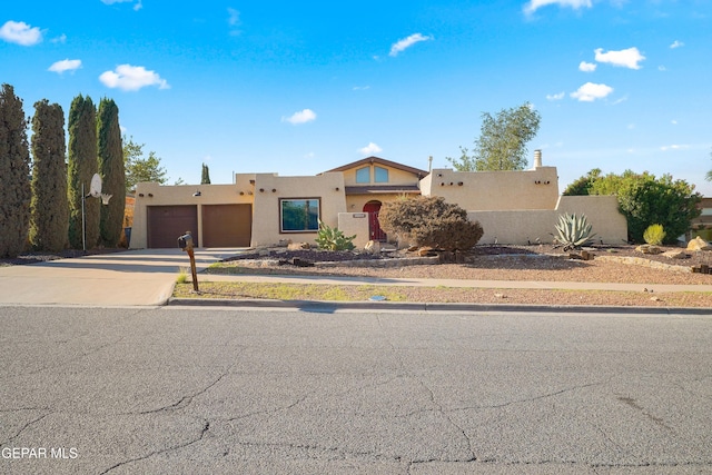 6604 Camino Fuente Dr, El Paso, TX 79912 - pueblo revival-style home with stucco siding, concrete driveway, and a garage