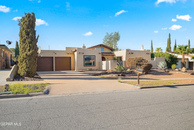 6604 Camino Fuente Dr, El Paso, TX 79912 - pueblo-style house with stucco siding, driveway, and an attached garage