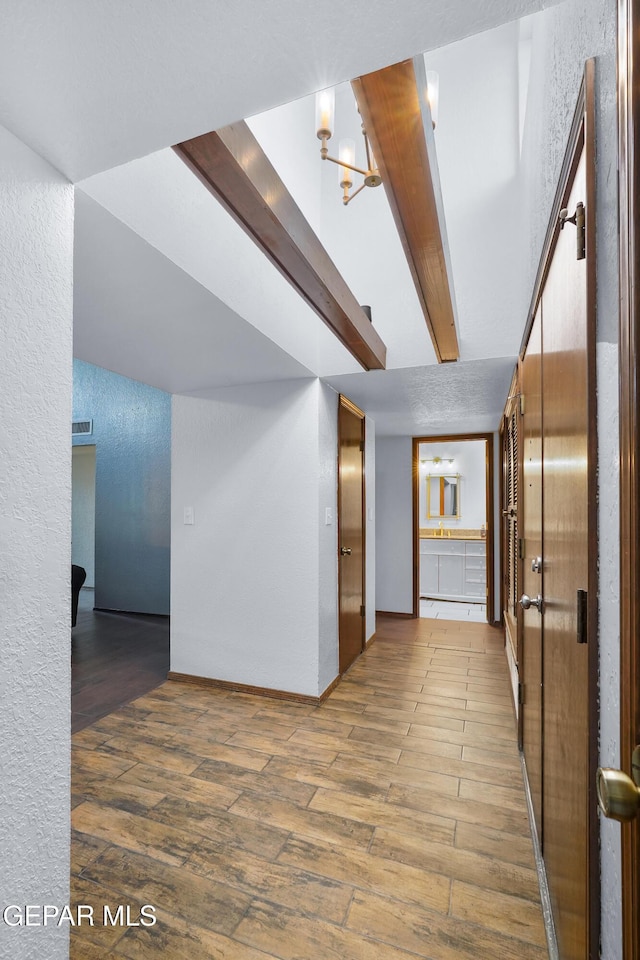 6604 Camino Fuente Dr, El Paso, TX 79912 - hall with wood finished floors, a chandelier, a textured wall, and beamed ceiling