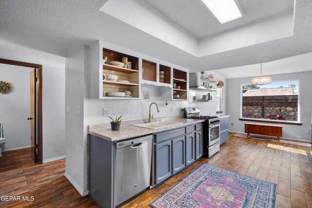 6604 Camino Fuente Dr, El Paso, TX 79912 - kitchen with appliances with stainless steel finishes, open shelves, light countertops, dark wood-style flooring, and wall chimney range hood
