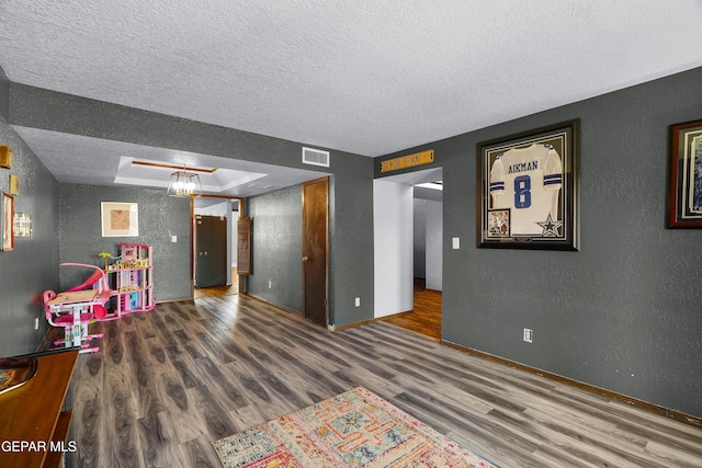 6604 Camino Fuente Dr, El Paso, TX 79912 - game room featuring a textured wall, a textured ceiling, wood finished floors, and a raised ceiling