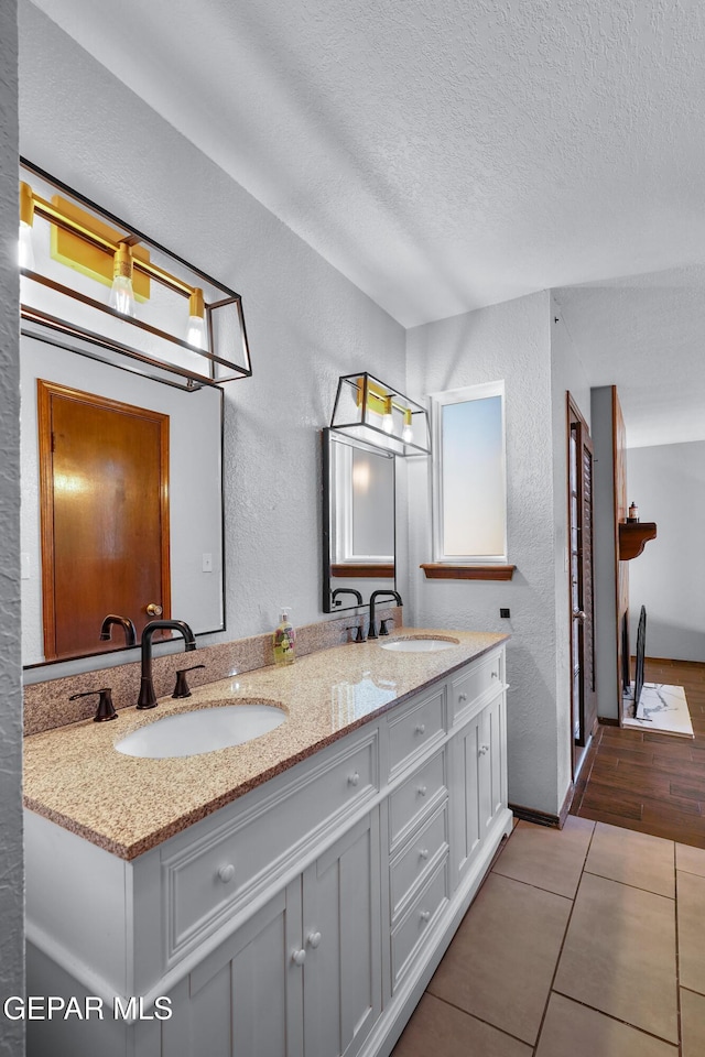6604 Camino Fuente Dr, El Paso, TX 79912 - full bath featuring a textured wall, double vanity, a textured ceiling, and tile patterned flooring