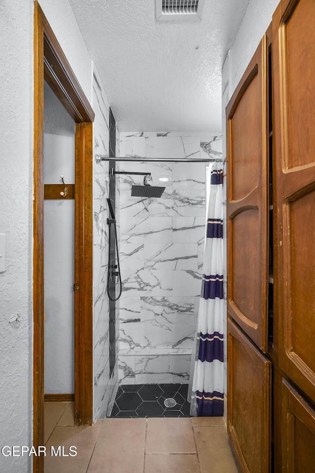 6604 Camino Fuente Dr, El Paso, TX 79912 - bathroom featuring a marble finish shower, a textured ceiling, and tile patterned flooring