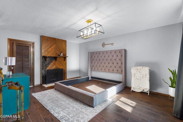 6604 Camino Fuente Dr, El Paso, TX 79912 - bedroom featuring wood finished floors, a fireplace, a chandelier, and a textured ceiling