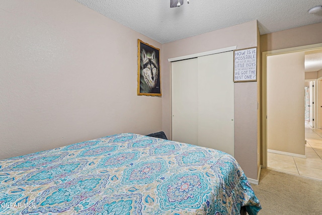 13344 Jonathan Elias Ct, El Paso, TX 79938 - bedroom featuring a closet, light tile patterned flooring, light colored carpet, and a textured ceiling