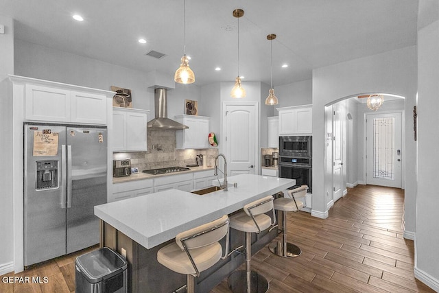 991 Hull St, El Paso, TX 79928 - kitchen featuring appliances with stainless steel finishes, wall chimney range hood, arched walkways, dark wood finished floors, and recessed lighting