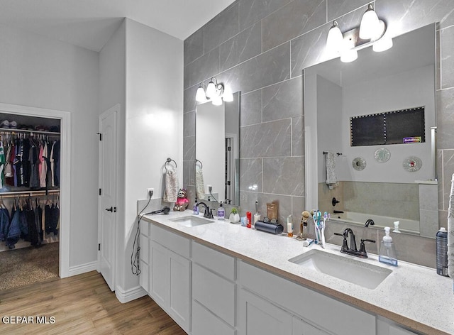 991 Hull St, El Paso, TX 79928 - full bath featuring double vanity, a garden tub, wood finished floors, tile walls, and a walk in closet