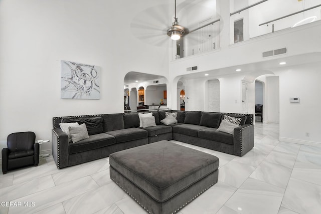 12247 Chisholm Pass Dr, El Paso, TX 79936 - living room featuring arched walkways, a ceiling fan, light marble finish flooring, and a high ceiling