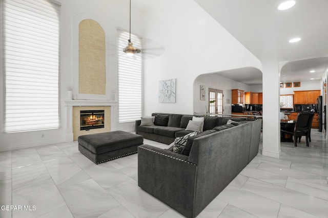 12247 Chisholm Pass Dr, El Paso, TX 79936 - living area with arched walkways, recessed lighting, a tiled fireplace, light marble finish floors, and a ceiling fan