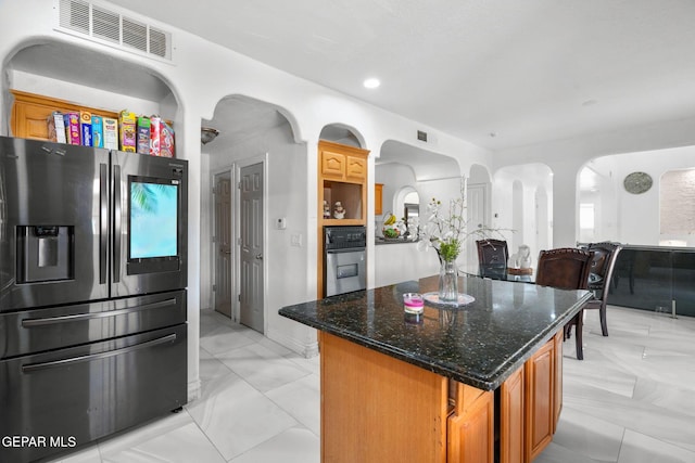 12247 Chisholm Pass Dr, El Paso, TX 79936 - kitchen with stainless steel appliances, arched walkways, a kitchen island, light marble finish floors, and dark stone counters