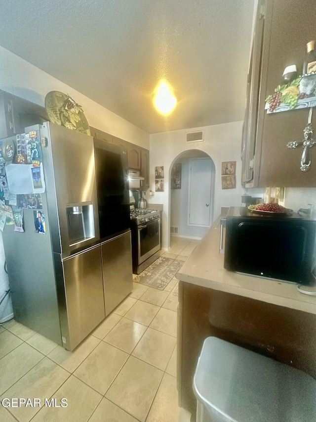 12036 Valley Quail Dr, El Paso, TX 79936 - kitchen featuring stainless steel appliances, arched walkways, light tile patterned flooring, ventilation hood, and light countertops