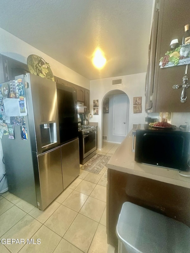 12036 Valley Quail Dr, El Paso, TX 79936 - kitchen featuring stainless steel appliances, arched walkways, light tile patterned floors, light countertops, and extractor fan