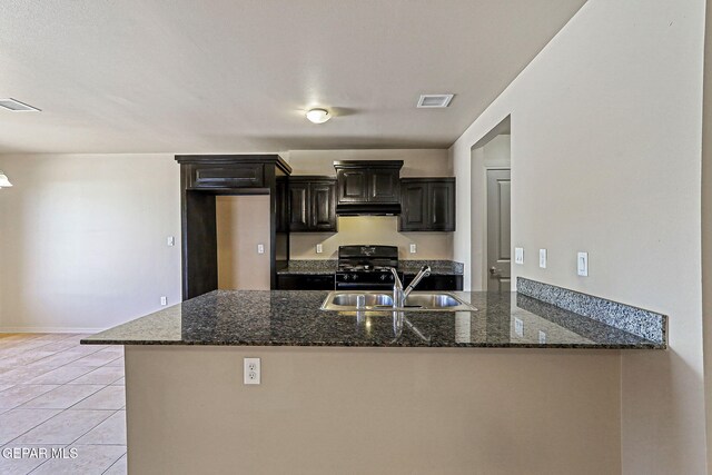 708 Cora Ruecker, El Paso, TX 79928 - kitchen with range with gas stovetop, under cabinet range hood, dark stone countertops, and light tile patterned floors