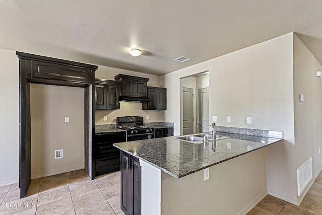 708 Cora Ruecker, El Paso, TX 79928 - kitchen with black gas stove, under cabinet range hood, a peninsula, dark stone counters, and dark cabinets