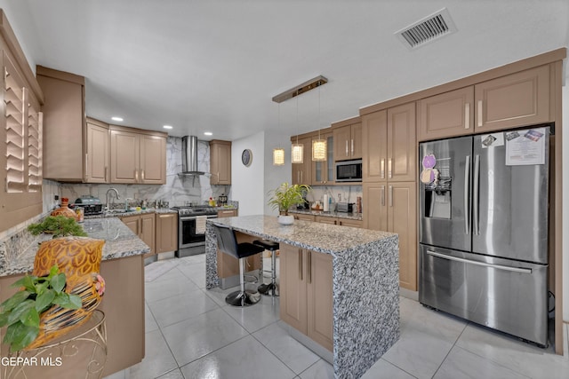 11749 Socorro Rd, Socorro, TX 79927 - kitchen featuring appliances with stainless steel finishes, wall chimney exhaust hood, light stone counters, tasteful backsplash, and a center island