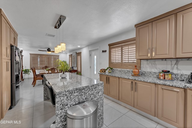 11749 Socorro Rd, Socorro, TX 79927 - kitchen featuring a ceiling fan, light stone countertops, light tile patterned floors, freestanding refrigerator, and decorative light fixtures